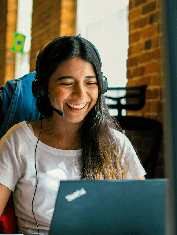 Lächelnde Frau mit einem Headset, die an einem Laptop arbeitet.